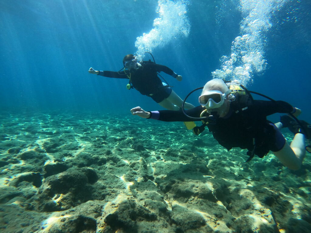 Two scuba divers exploring the reef on a boat and shore dive with Sun Seals Divers